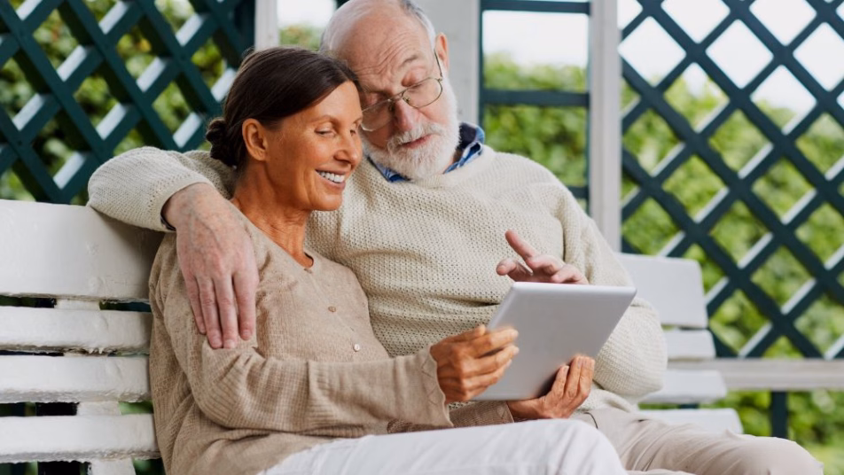 para uśmiechniętych seniorów korzysta z tableta