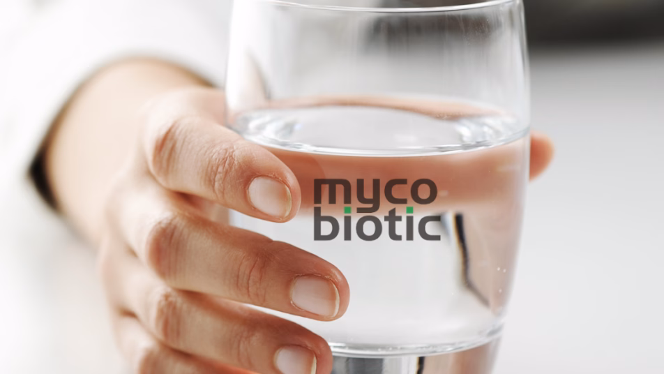 Ręka trzymająca szklankę wody z logo Mycobiotic na szkle