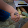 tatuaż Mycobiotic KIDS na ręku dziecka, w tle kolorowa kreda